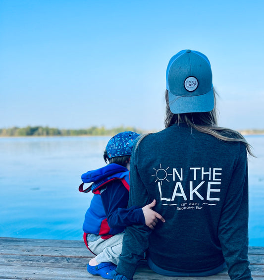Outdoor apparel for cold weather, Cozy outdoor wear, Cold-weather gear, outdoor clothing, woman sitting on a dock with little boy facing the water in grey long sleeve shirt