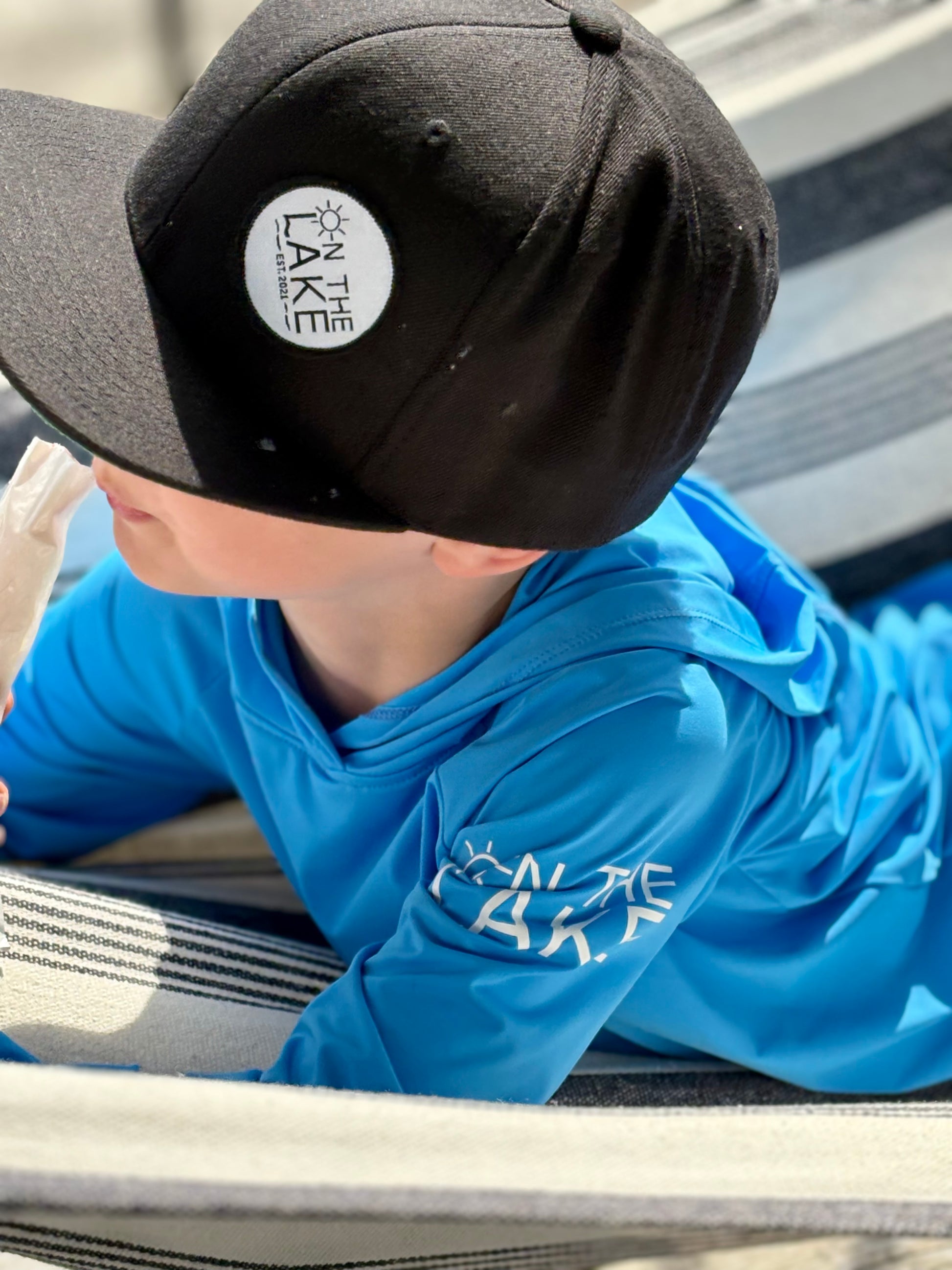 Child wearing UV long sleeve hooded shirt, UPF 50+ fishing hoodie during a sunny day on the lake