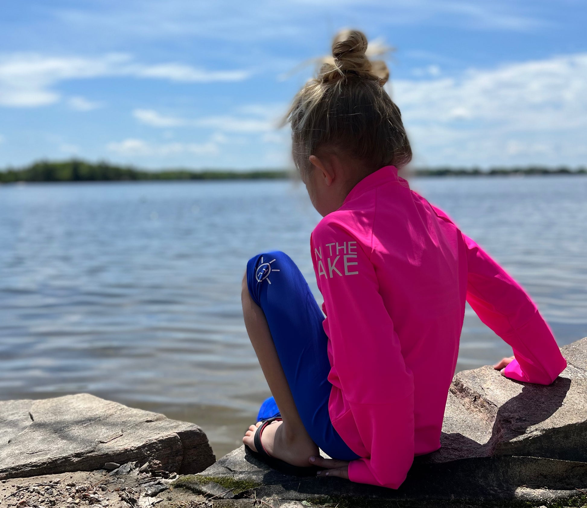 Kids UPF 50+ natural sun protection swimwear clothing Canada, UPF 50+ swimwear, Sun protective clothing, UV swimwear, Sun-safe apparel, UV protection for water activities, Sun-blocking swimwear, Family sun protection clothing, Sun safe boating attire, girl at the edge of lake with pink UPF shirt and blue shorts